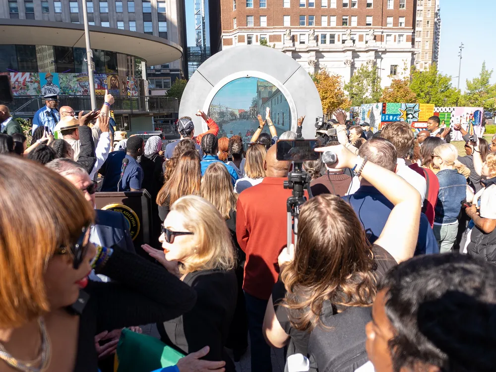 A crowd in front of a portal sculpture