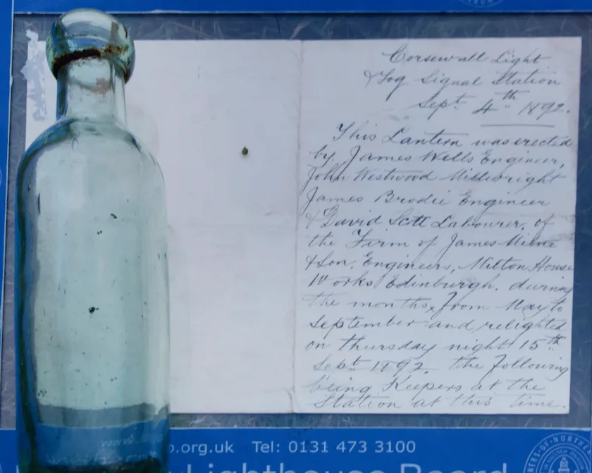 Glass bottle next to paper with cursive handwriting