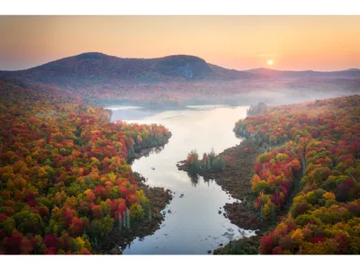 Seemingly still waters wind through colorful canopies displaying warm autumn hues on a hazy September morning.