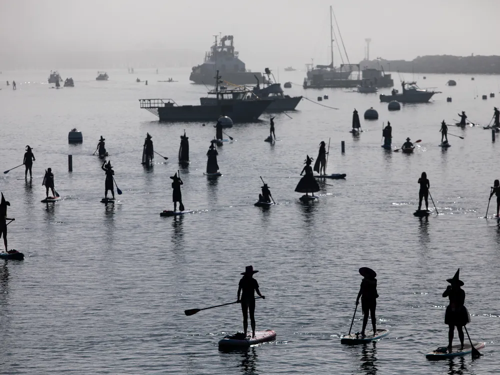 Silhouettes of people dressing as witches on standup paddleboards