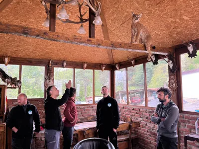 Dime Melovski gestures at lynx displayed in a hunter&rsquo;s lodge in North Macedonia. The hunters found the lynx dead on the road and asked the scientists for permission to taxidermy it.