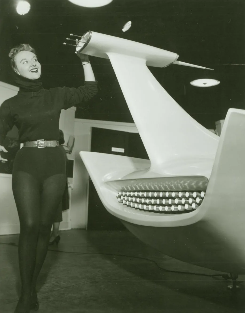 A woman poses next to a model of the Studebaker-Packard Astral