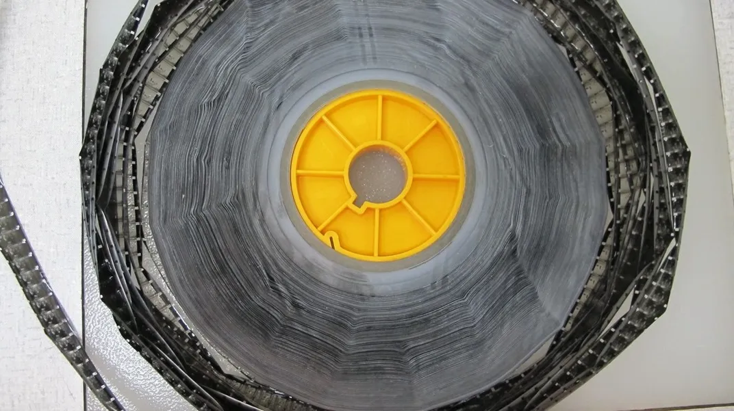 Yellow reel with black, decaying film on white background